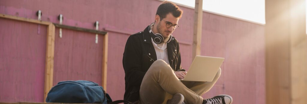 Young-man-sitting-on-platform-using-laptop-scaled.jpg